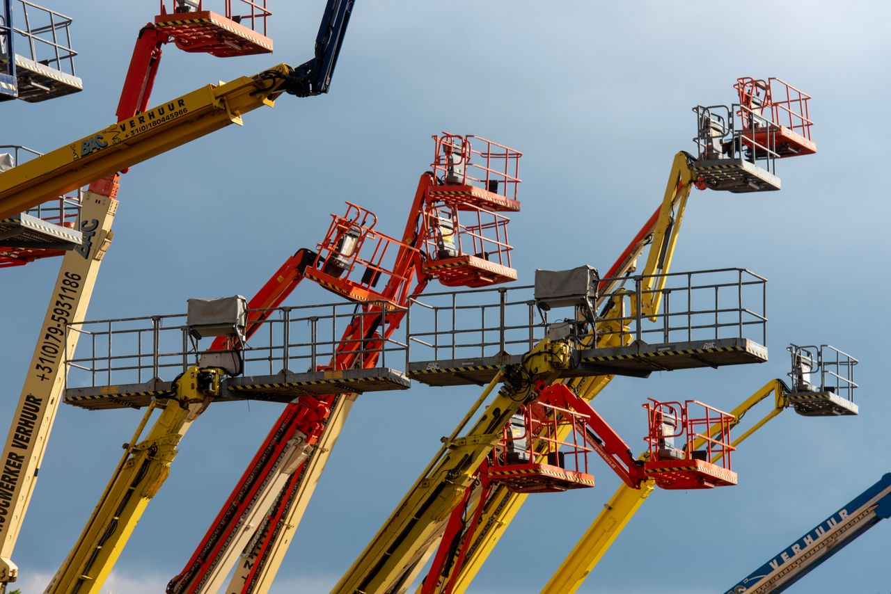 services-01 Vibrant boom lifts reaching skyward, showcasing industrial machinery against a clear blue backdrop.