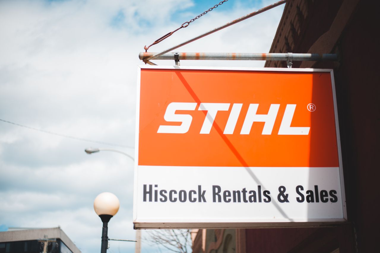 Outdoor STIHL sign in urban environment with clear blue skies and visible streetlamp.